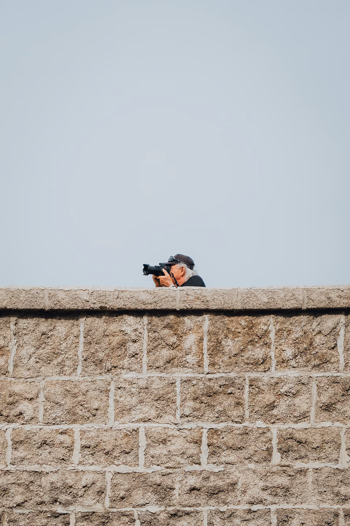 Photographer leaning over a stone wall
